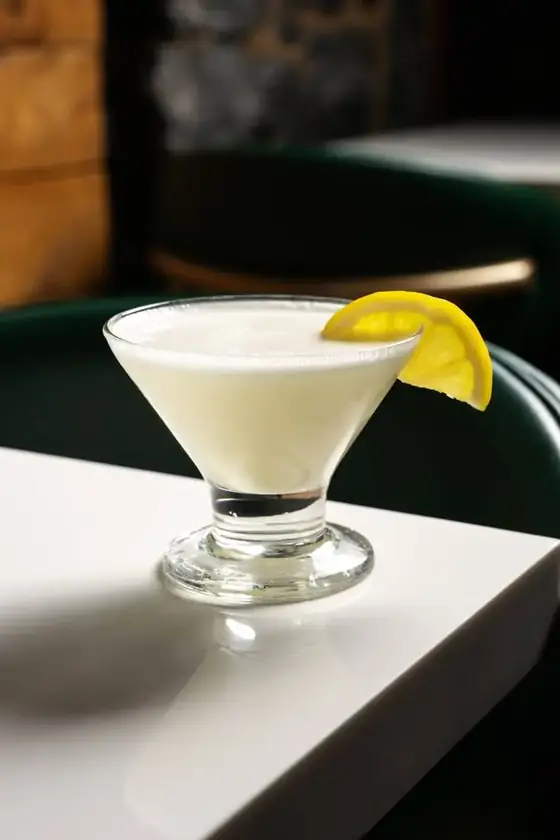 A creamy lemon cocktail in a coupe glass with a lemon slice