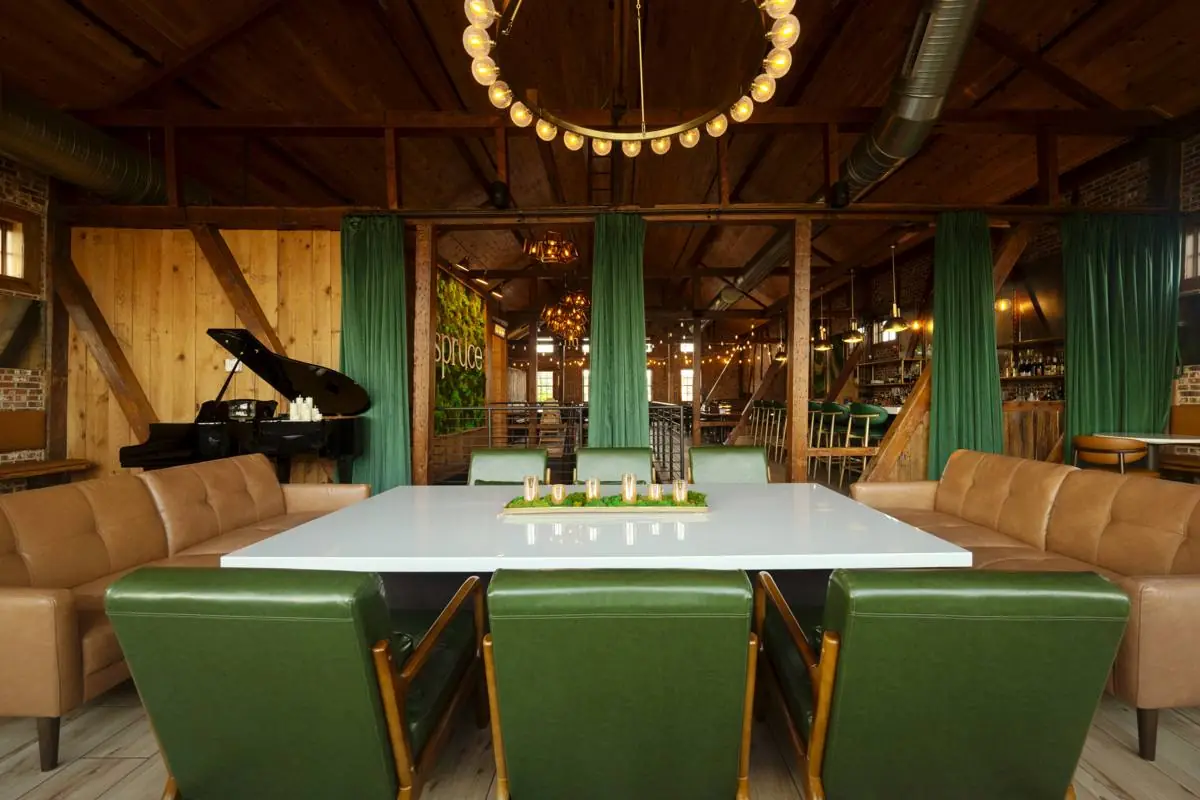 A wider view of the lounge seating area with the table, green chairs, and the loft behind