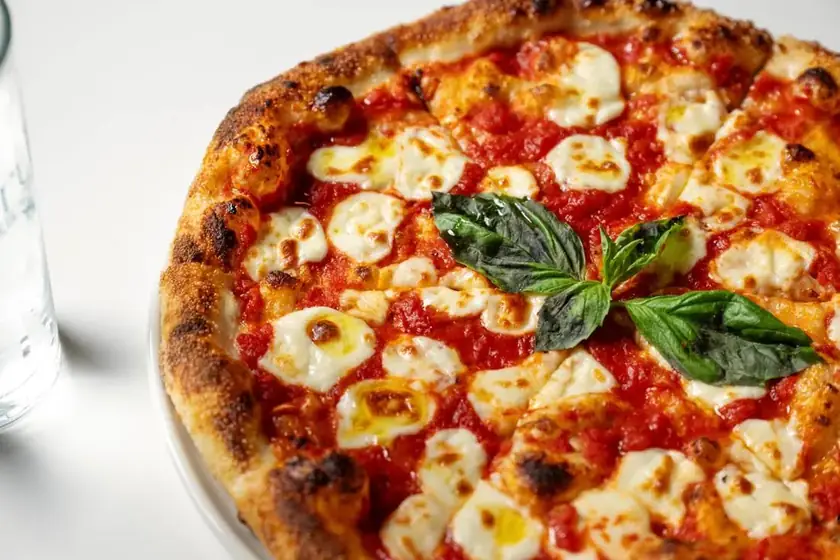 Pizza topped with fresh mozzarella, tomato sauce, and basil