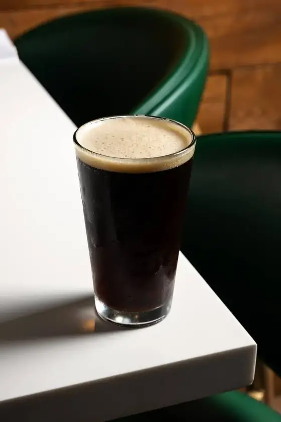 A pint of dark stout beer on a white table