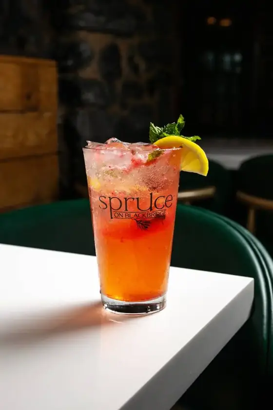 A strawberry lemonade with mint and a lemon wedge in a Spruce on Blackbridge glass